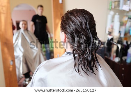 Reflection in mirror woman brunette in hairdressing beauty salon.