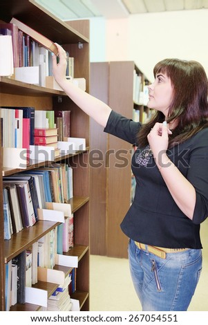Beautiful Woman in the library takes the book from the shelf