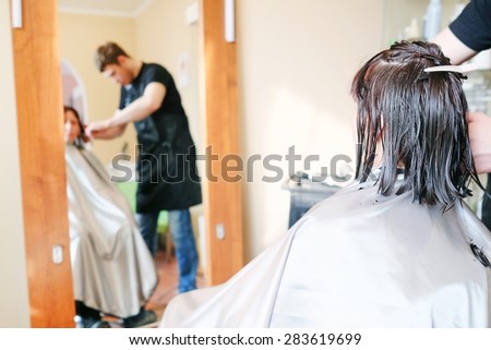 Hairdresser making a haircut for a brunette women