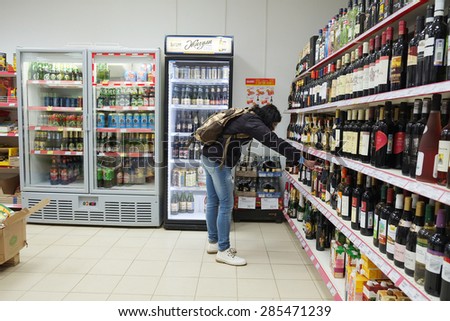 MOSCOW, RUSSIA  -  APRIL 07, 2015: Woman choosing a bottle of wine in supermarket store Pyaterochka. Supermarket Pyaterochka with the most affordable prices. Russia\'s largest retailer.