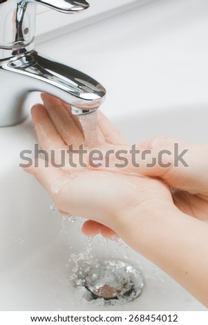 washes his hands under running water in the bathroom light