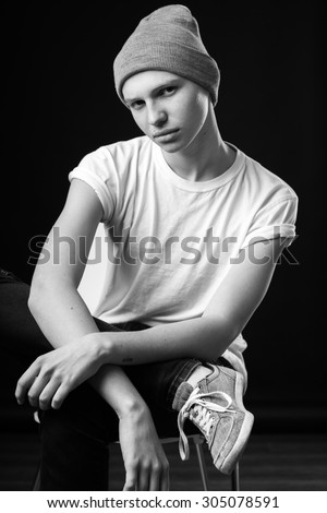 handsome young man working as an actor and posing for the camera in a dark studio uniform background showing emotion. black and white shot of a high-contrast, easy