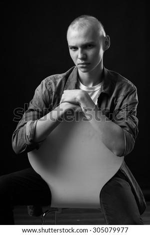 handsome young man working as an actor and posing for the camera in a dark studio uniform background showing emotion. black and white shot of a high-contrast, easy