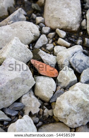 Red rock amongst grey rocks on a beach