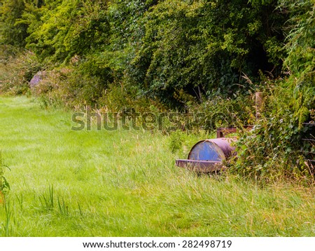 Grass roller hiding in a hedgerow of a field in County Westmeath, Ireland. The roller is used to level the field after being trampled by cattle during the wetter months.