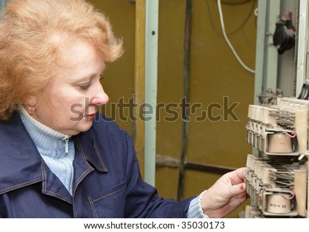 Operator woman-engineer  in machine room (elevator) check the mechanical equipment.