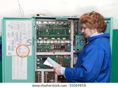 Operator woman-engineer  in machine room (elevator) near electronic cabinet.