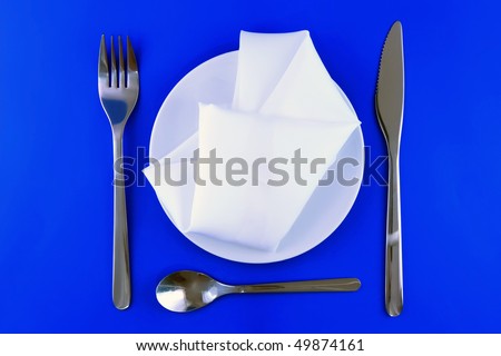 Table serving- knife, spoon, fork, spoon and silk napkin  a on blue   background.