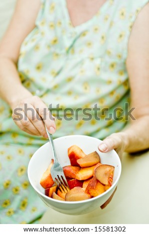 An older woman offering a bowl of fruit.