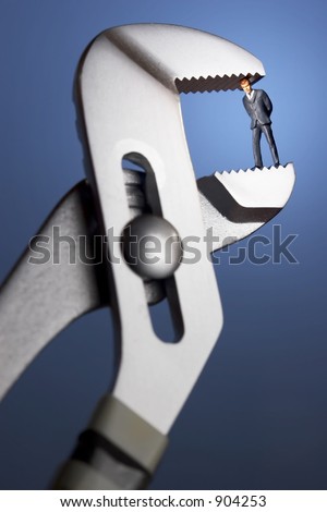 Business figurines in a clamp / blue background and spotlight
