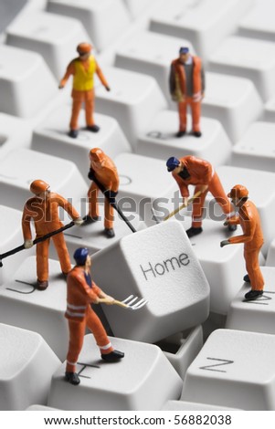 Worker figurines posed around the Home key on a computer keyboard.
