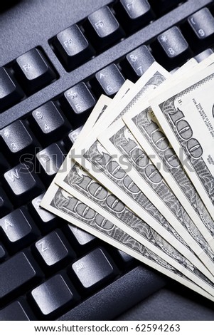 100 dollar bills fanned out on top of a computer keyboard