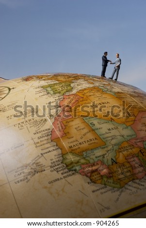 Business figurines on earth globe shaking hands / portrait
