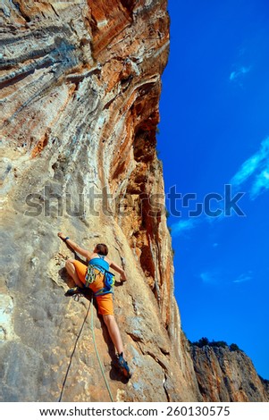 female rock climber climbs on a rocky wall