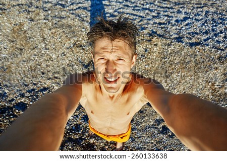 young happy man make selfie on the beach. pictures of himself on top