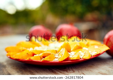 Sliced fruits arrangement. Delicious Persimmon fruit with bananas and oat-flakes ready to serve. laid out on a red plate on a wooden background.