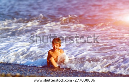 laughing boy  looks into the camera on a beach at sunset
