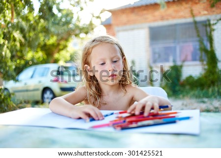 Cheerful little girl with sketch pen drawing in outdoor