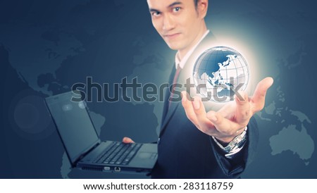 Conceptual image of internet information technology. Digital imaging of young man in formal suit holding laptop showing the world with his hands