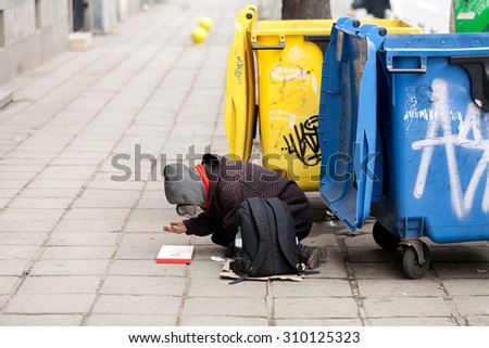 Sofia, Bulgaria, January 19, 2014. A homeless man is begging for money and hope at street next to a trash bin. Poverty is big problem in Bulgaria, member of EU since 2007.