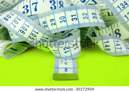 A measuring tape isolated against a lime green background