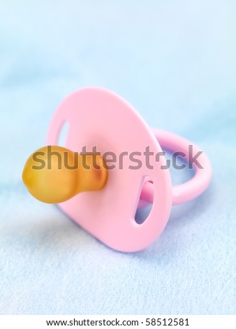 A pink pacifier isolated against a blue background