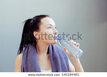 Young woman at the gym drinks water