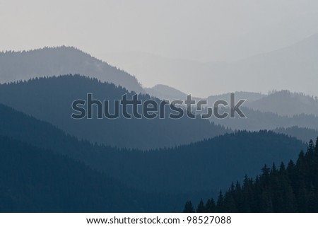 Mountain landscape with a chain of hills covered with forests in the evening at summer