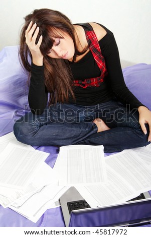 A woman looks tired/upset/exasperated/worried while paying bills/working/doing a budget.