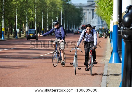 LONDON, UK - CIRCA May 2012: Man cycling and pushing another bicycle on the Mall.