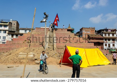 KATHMANDU, NEPAL - MAY 14, 2015: A man carries a large Nepal flag on Durbar Square, a UNESCO World Heritage Site.