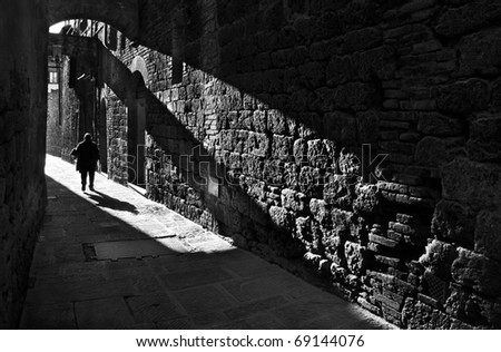 Silhouette of a pedestrian in a small street of San Gimignano , Italy, black and white photography