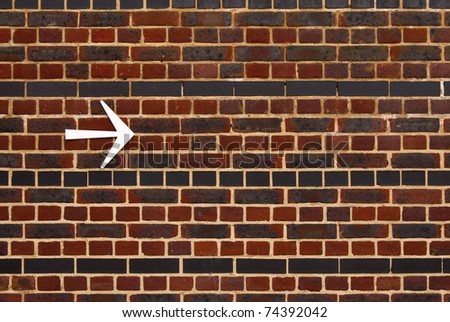 Bright arrow pointing the right direction on a brick wall