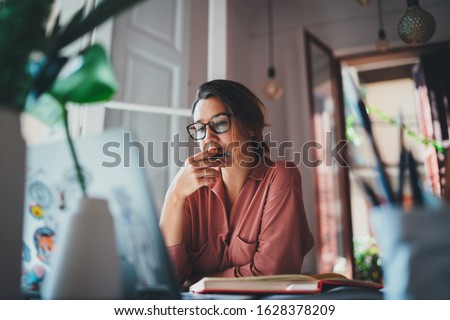 Young businesswoman thinking about something while sitting front open portable laptop computer reading email from client, long hours of work concept