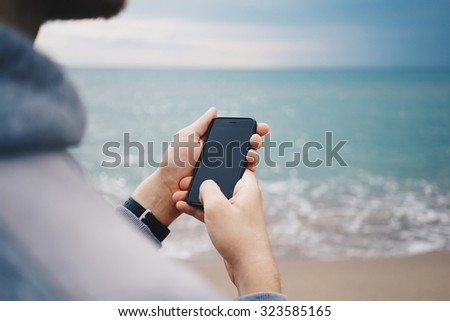 Close up of a man checking smartphone at the sea