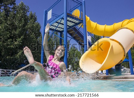 Summertime fun at the water park girl splashing on the slide