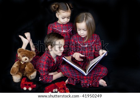 Children reading before bedtime the night before christmas