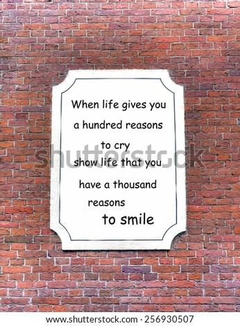 red brick wall background with a white board attached. On the board a quote about  life