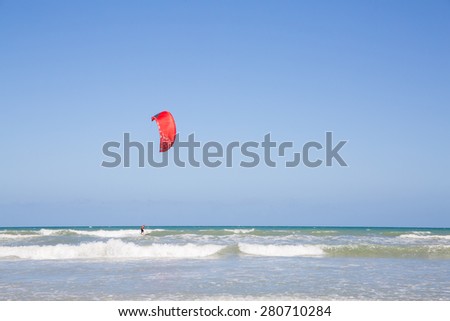 COCOA BEACH, FL/USA - APRIL 9, 2015: A man kitesurfs in Atlantic Ocean. Kitesurfing is a style of kiteboarding specific to wave riding, using standard surfboards or specifically shaped boards.