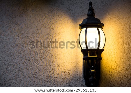Outdoor light fixture on in the dark on a textured background