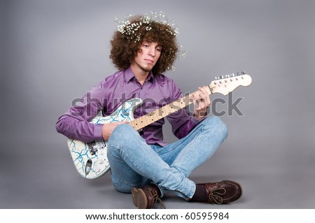 The young guy with curly hair and a guitar in hands.