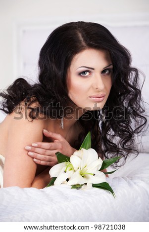Beautiful young woman with a flower laying on the bed
