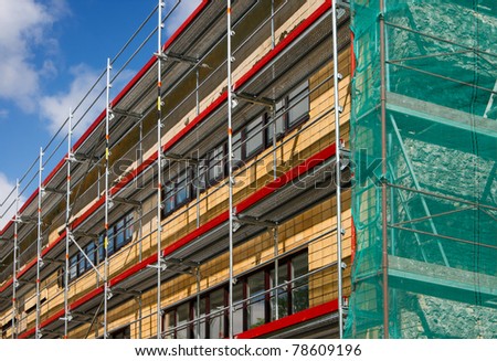 Corner view of a building with scaffolding enclosed in green safety fabric