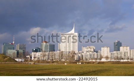 skyline of the danube city on the other riverside of the danube river in vienna, austria. bright afternoon lighting under stormy sky.
