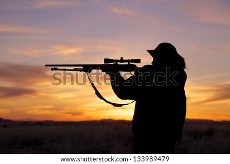 Woman Rifle Hunter Silhouetted at Sunset