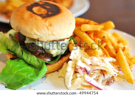 Sumptuous looking hamburger and fries with raw salad. Suitable for concepts such as diet and nutrition, healthy eating and lifestyle, and food and beverage.