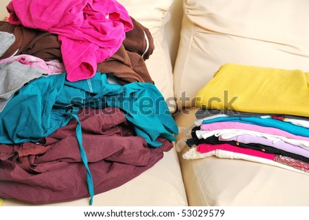 Messy clothes and folded clothes on sofa depicting a contrast.