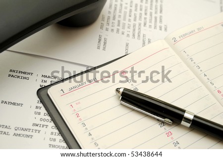 Capped black pen on planner with phone signifying concepts such as office and business, planning for the new year, financial budget and work related objects