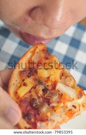 Top down view of Asian man eating pizza.