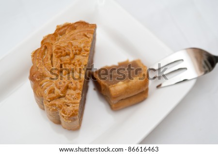 Delicious cut mooncake on white plate with dessert fork.